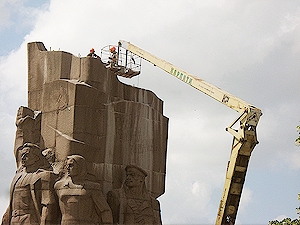 С помощью подъемного крана и люльки двое рабочих поднялись к верху памятника и установили там крепления для будущего переноса. Фото автора.